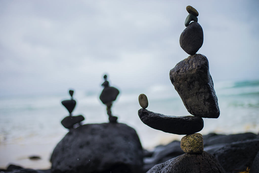 Stones balancing vertically, backed by ocean.